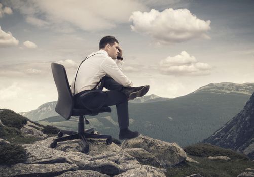 Young businessman sitting on chair and looking at landscape