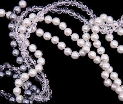 White, black and grey pearls on the black silk background 