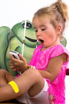 child playing with smartphone with a frog in the background