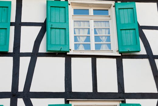 Shuttered window in an ancient timber frame house in Germany with pretty green shutters and lace curtains  exterior architectural background