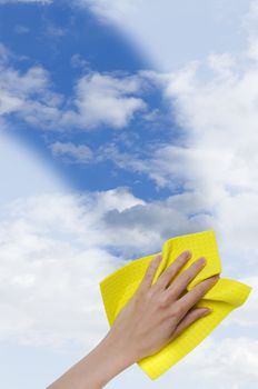 hand cleaning window making it easier to see blue sky through it cropped vertically