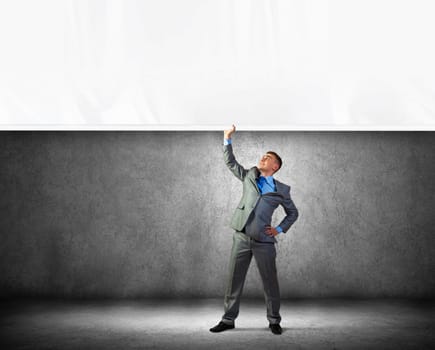 Image of young businessman pulling blank banner from above