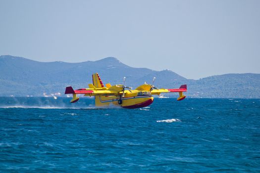 Firefighting airplane (airtanker, water bomber) flying over sea and taking water 