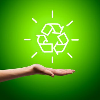 Recycling symbol in human hand against green background