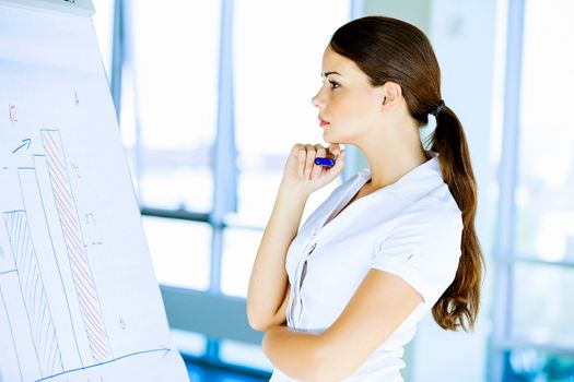 Image of young attractive businesswoman looking thoughtfully at project