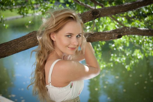 beautiful young woman on a background of foliage and water