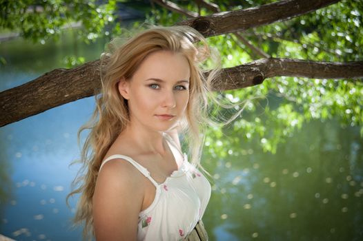 beautiful young woman on a background of foliage and water