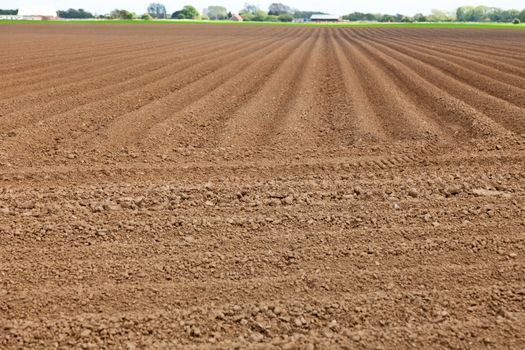 Ploughed field with farm in background