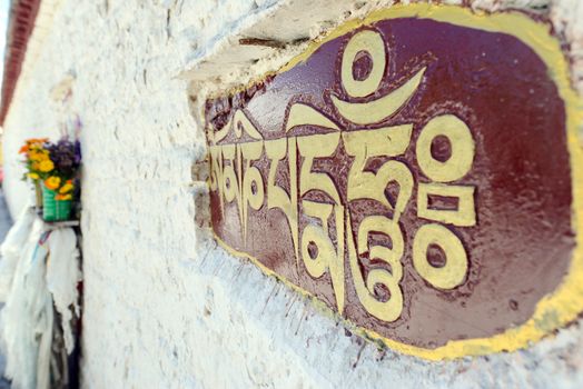 Golden buddhist prayer words on the wall in Tibet