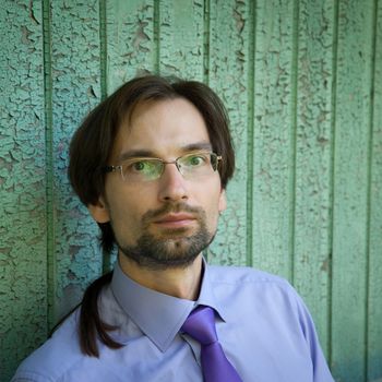 Successful man with glasses, a shirt and a tie against the wall.