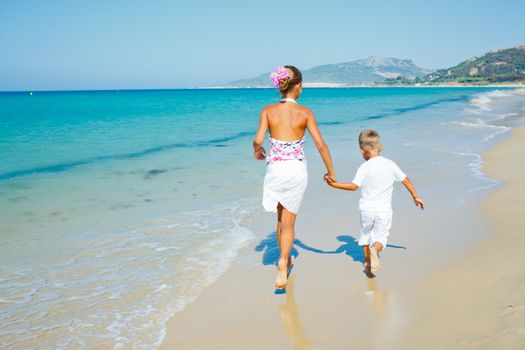 Back view of adorable happy boy and girl running on beach vacation