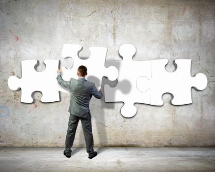 Image of businessman compiling macro white puzzle. Building business