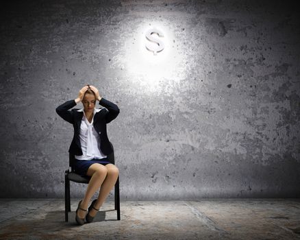 Image of depressed businesswoman sitting on chair with dollar sign above