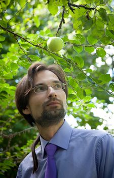 business man in a tie standing under an apple