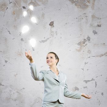 Image of attractive smiling businesswoman holding light bulbs on hand