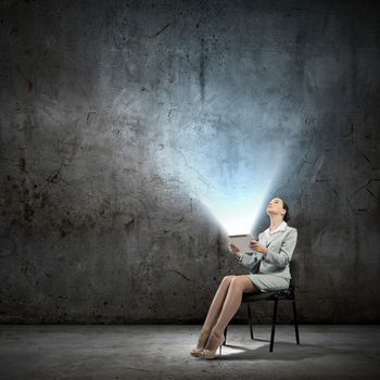 Image of businesswoman sitting on chair with tablet pc in hands