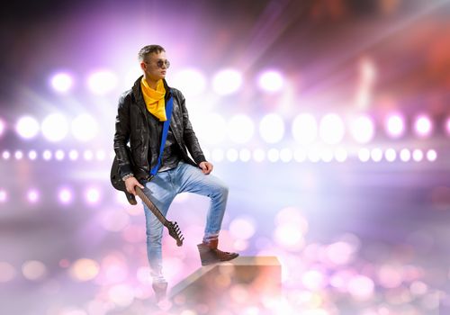 Young man, rock musician in jacket with guitar