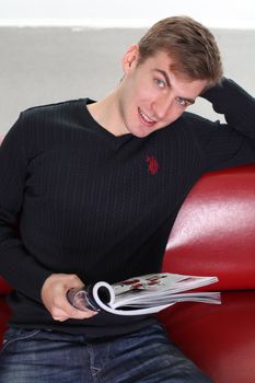 young man with magazine sitting on sofa