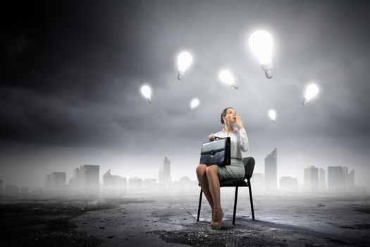 Image of businesswoman sitting on chair with suitcase in hands