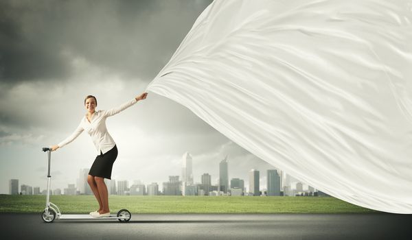 Image of attractive businesswoman riding a scooter. Place for text