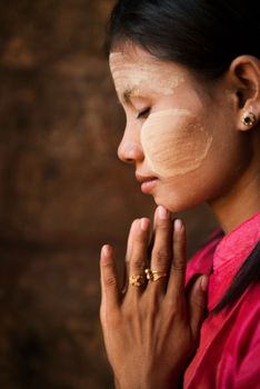 Beautiful traditional Myanmar girl is praying inside temple.
