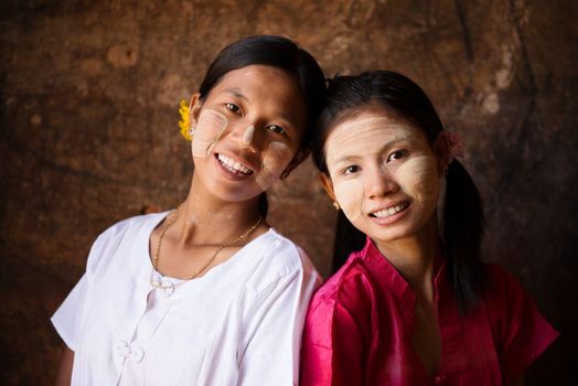 Portrait of two beautiful young traditional Myanmar girls smiling together.