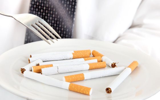Man Hold a Fork and Plate with Many Cigarettes closeup
