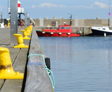 Docks with yellow bollards. A red boat in the background.