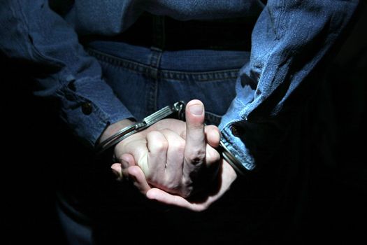 Man in Handcuffs shows Middle Finger gesture in the Dark Room Closeup