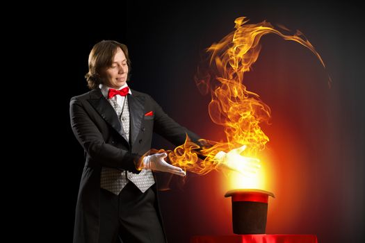 Image of magician holding hat with fire flames and fumes going out