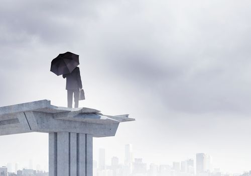 Image of businessman with umbrella standing at the edge of bridge