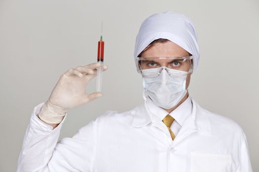 Confident surgeon holding a syringe against a white background