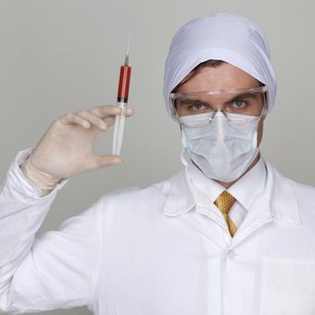 Confident surgeon holding a syringe against a white background