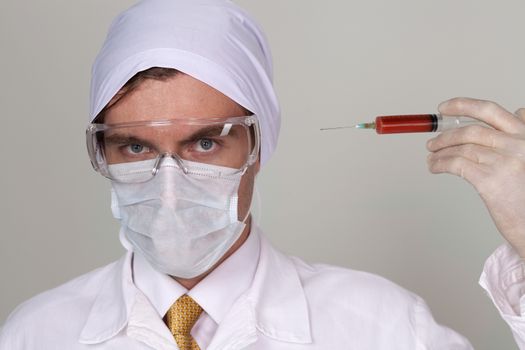 Confident surgeon holding a syringe against a white background