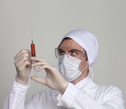 Confident surgeon holding a syringe against a white background