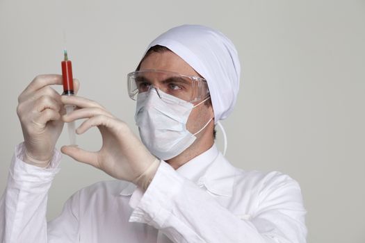 Confident surgeon holding a syringe against a white background