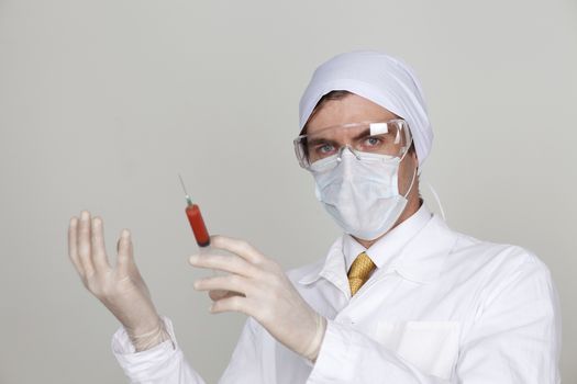 Confident surgeon holding a syringe against a white background