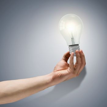 Close up image of human hand holding electrical bulb