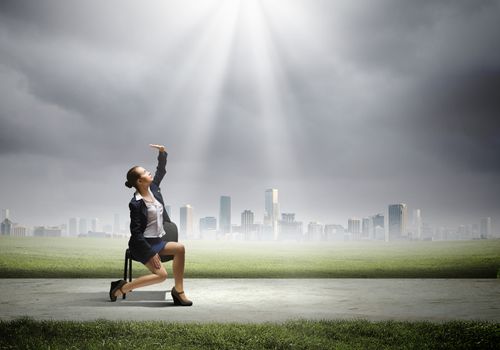 Image of businesswoman sitting on chair under sun lights