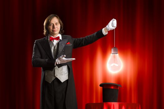 Image of man magician showing trick against color background