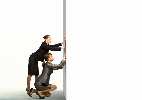 Two businesswoman pushing blank white banner. Place for text