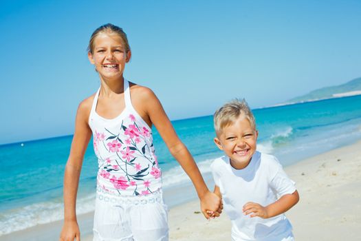 Adorable happy boy and girl running on beach vacation