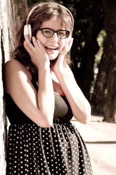 A vintage dressed girl listing to music in a urban environment.