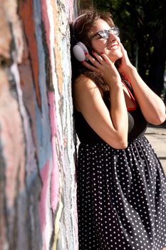 A vintage dressed girl listing to music in a urban environment.