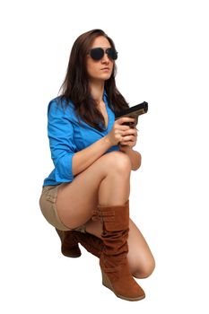 A lovely young brunette kneels, holding a modern handgun.  Isolated on a white background with generous copyspace.