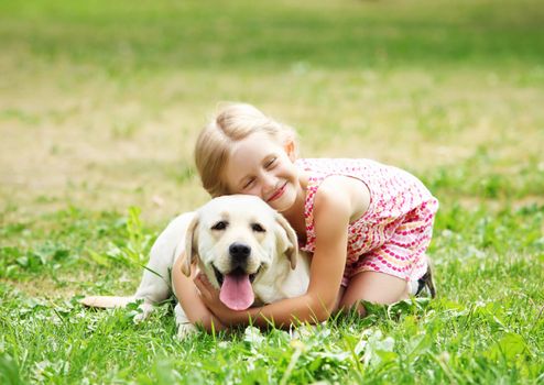 A little blond girl with her pet dog outdooors in park