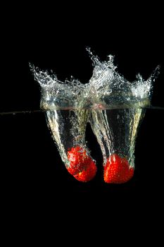 Colored red paprika in water splashes on black background