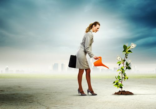 Image of businesswoman watering money tree with pot