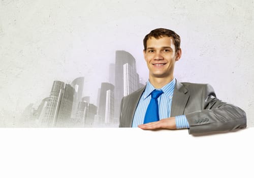 Businessman with blank banner standing against urban scenic. Place for text
