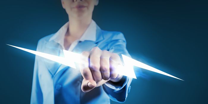 Image of powerful businesswoman holding lightning in fist